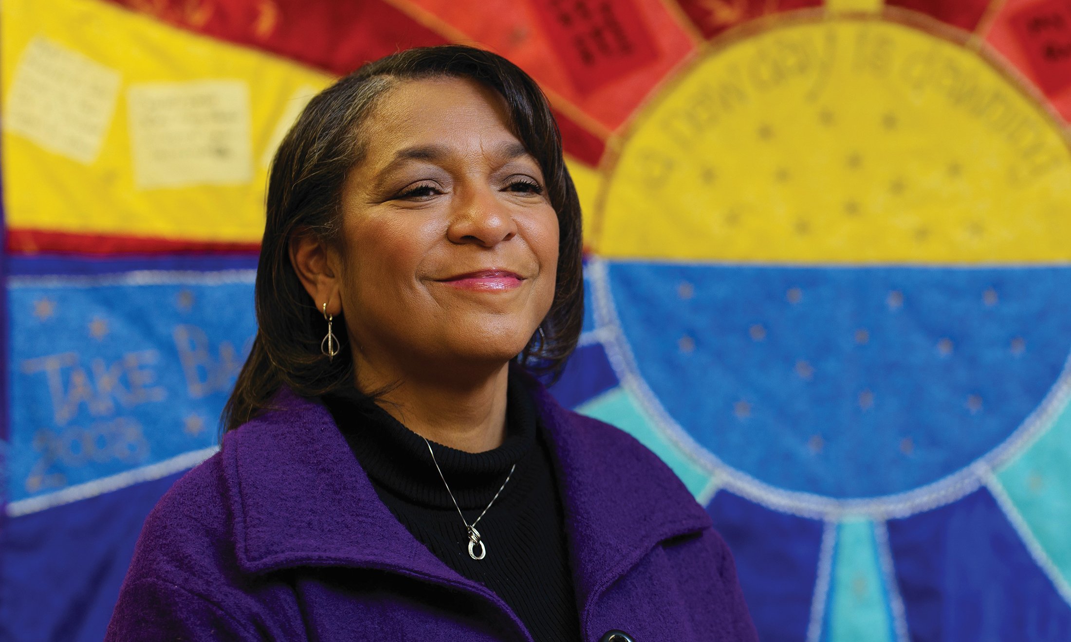 A woman smiling in front of a colorful background