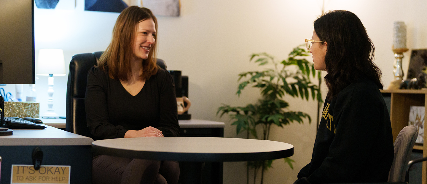 Young woman sits at table with an adviser.