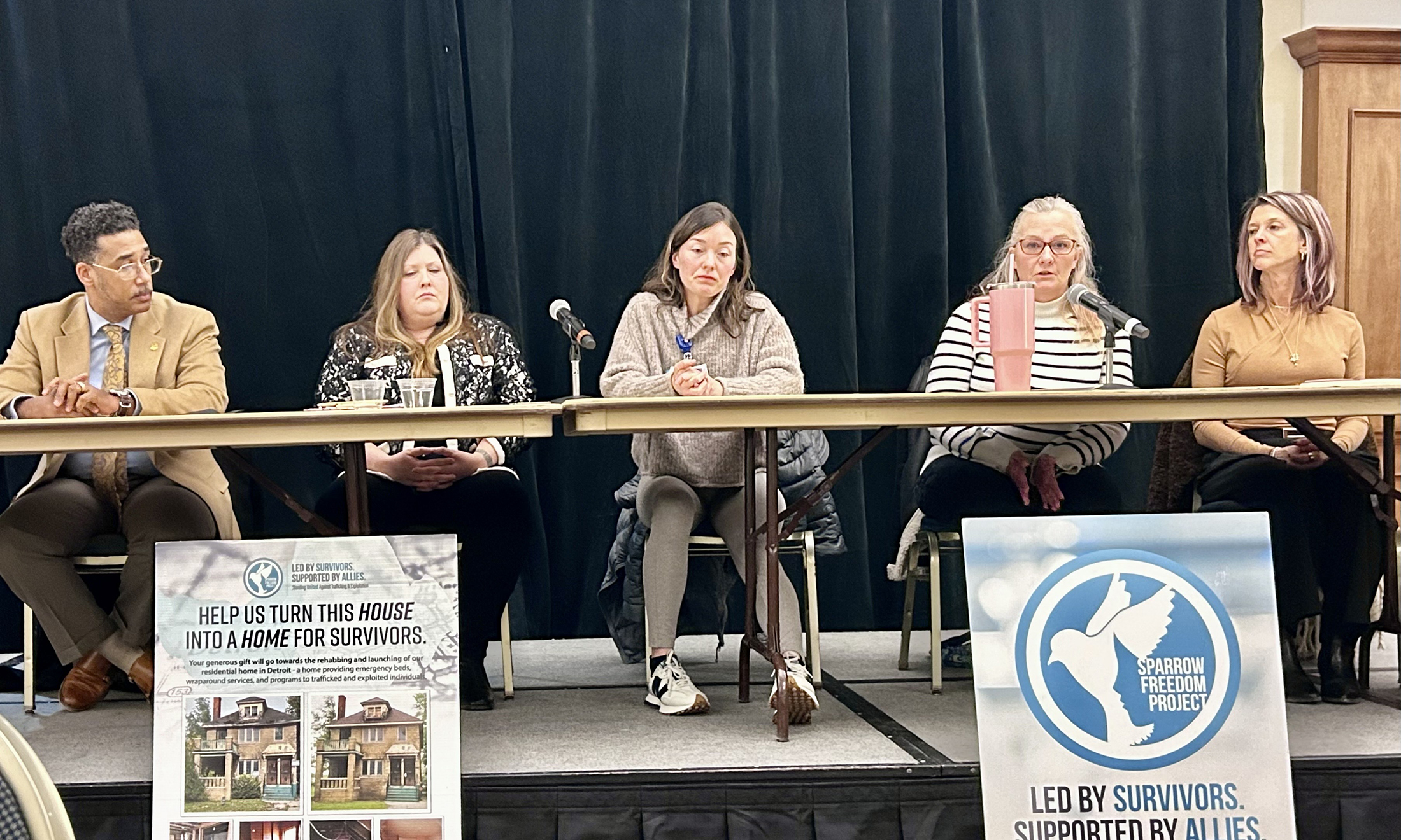 Panelists sit at a table on stage.