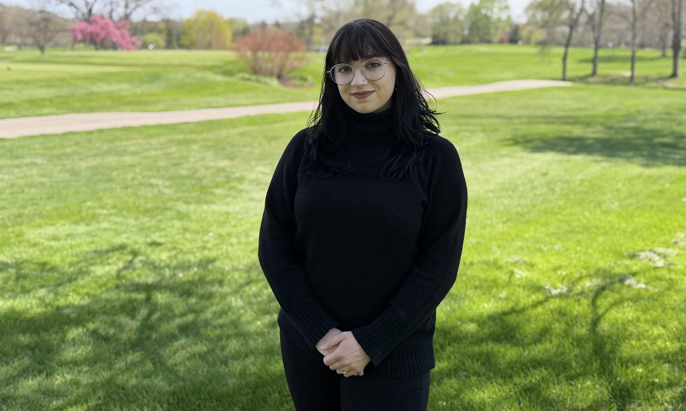 Sophia Vecchi poses for a photo outdoors near a grass field.