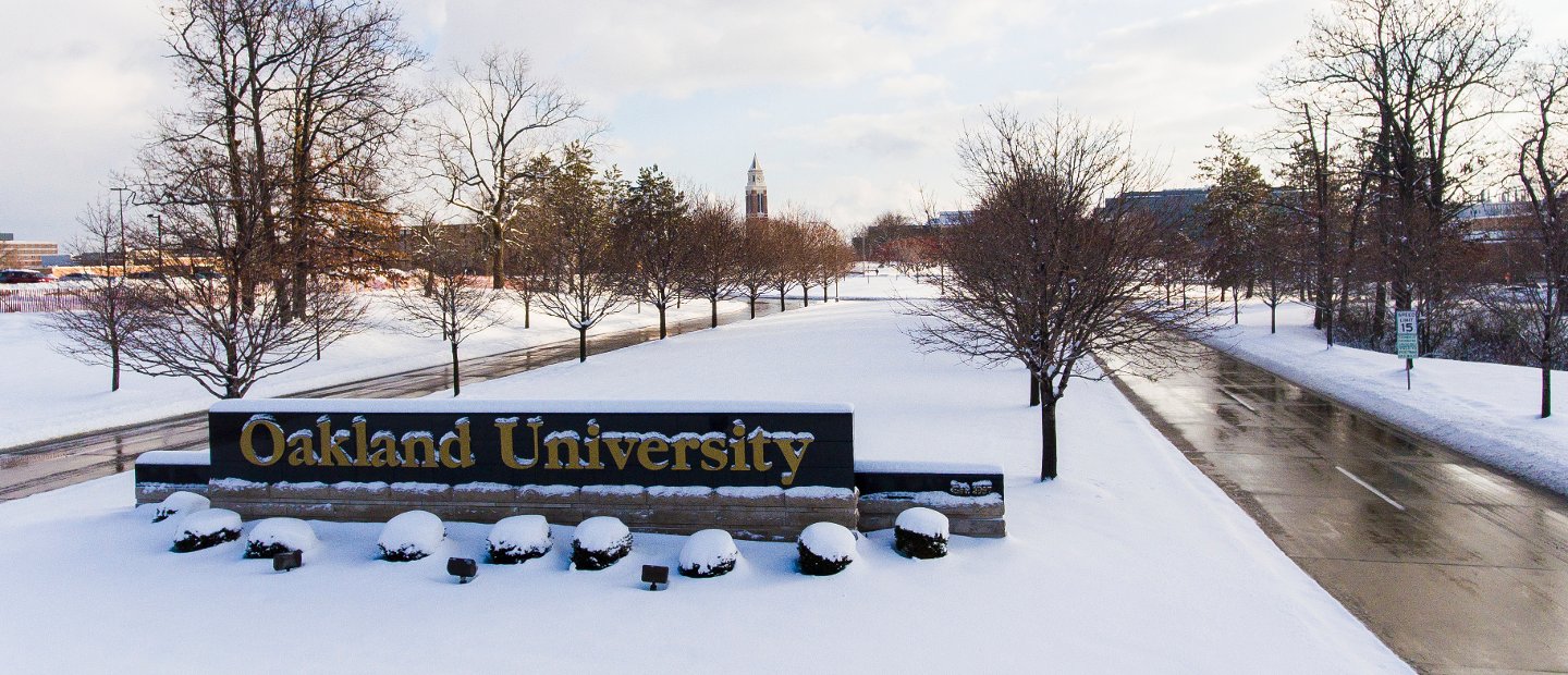 An Oakland University sign at the entrance to campus with snow on the ground.