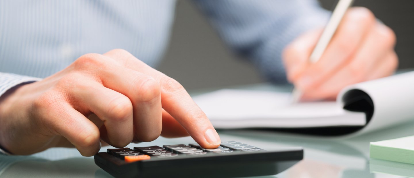 Hands writing in a notebook and using a calculator