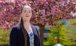 A student stands in front of blossoming trees