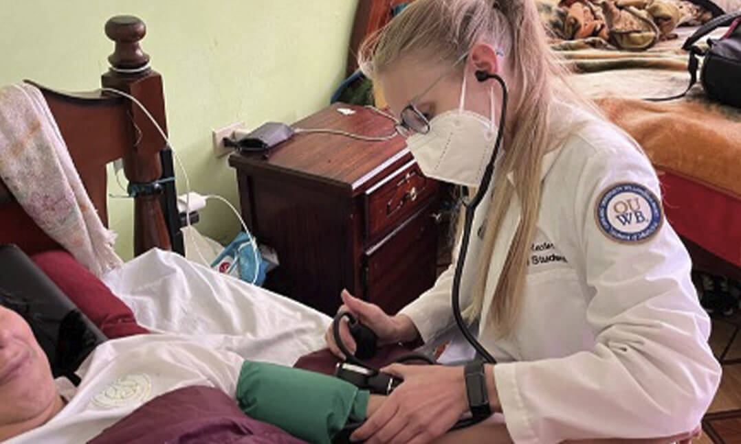 Dana Rector, M.D., OUWB '23, in Ecuador, 2023 helping a patient can’t get to the clinic very easily