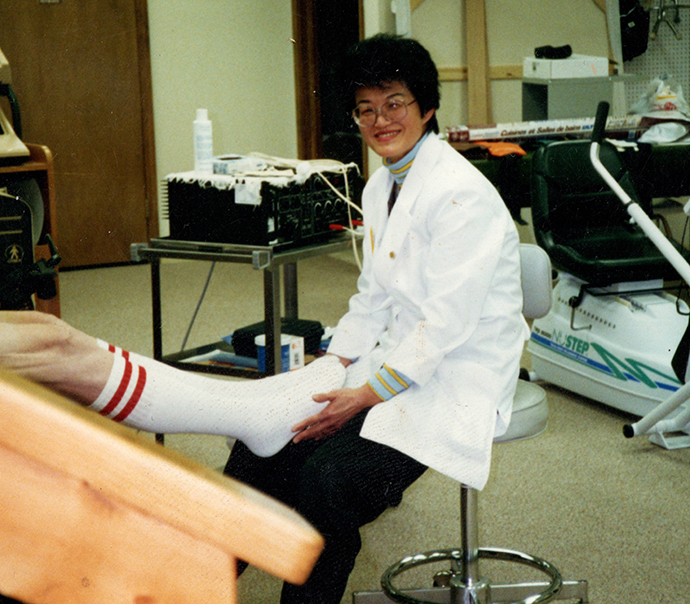 Marie looks up from treating a patient in a physical therapy clinic and smiles