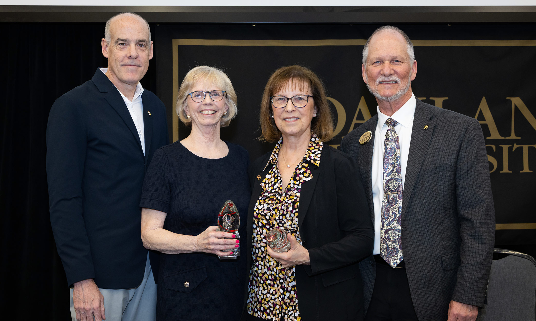 Kris Thompson and Melodie Kondratek hold awards, with Dr. Kevin Ball and Dr. John Krauss