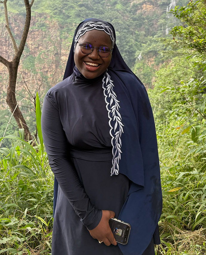 Marieme Samb in front of bright green trees, smiling