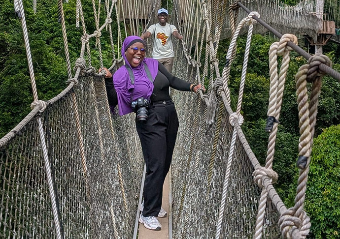 Marieme Samb on a rope bridge smiling, with Dr. Kwame Sakyi in the background
