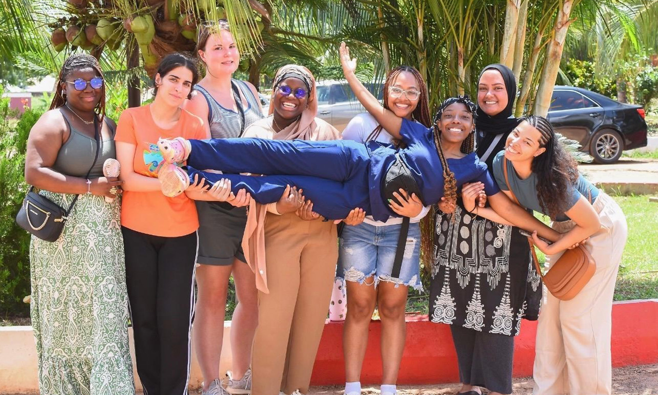 A group of students in front of palm trees smiling