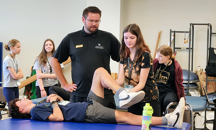 A camper practices passive stretching with a physical therapy student