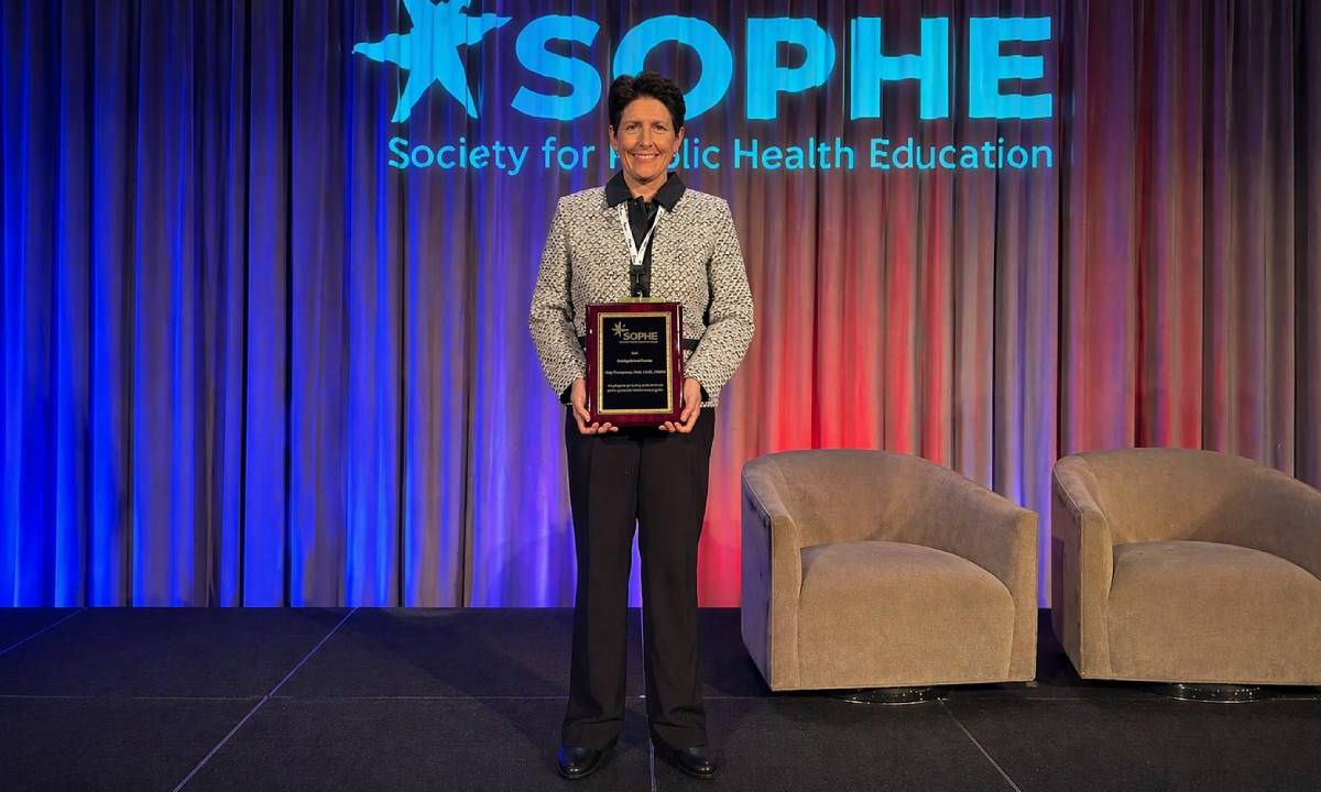 Dr. Amy Thomson holds an award at SOPHE conference