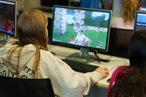 Two female students at monitor playing video game