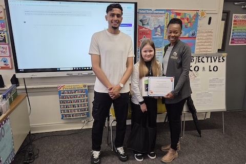 The Caniff book writing contest winner posing with a certificate and a group in a classroom