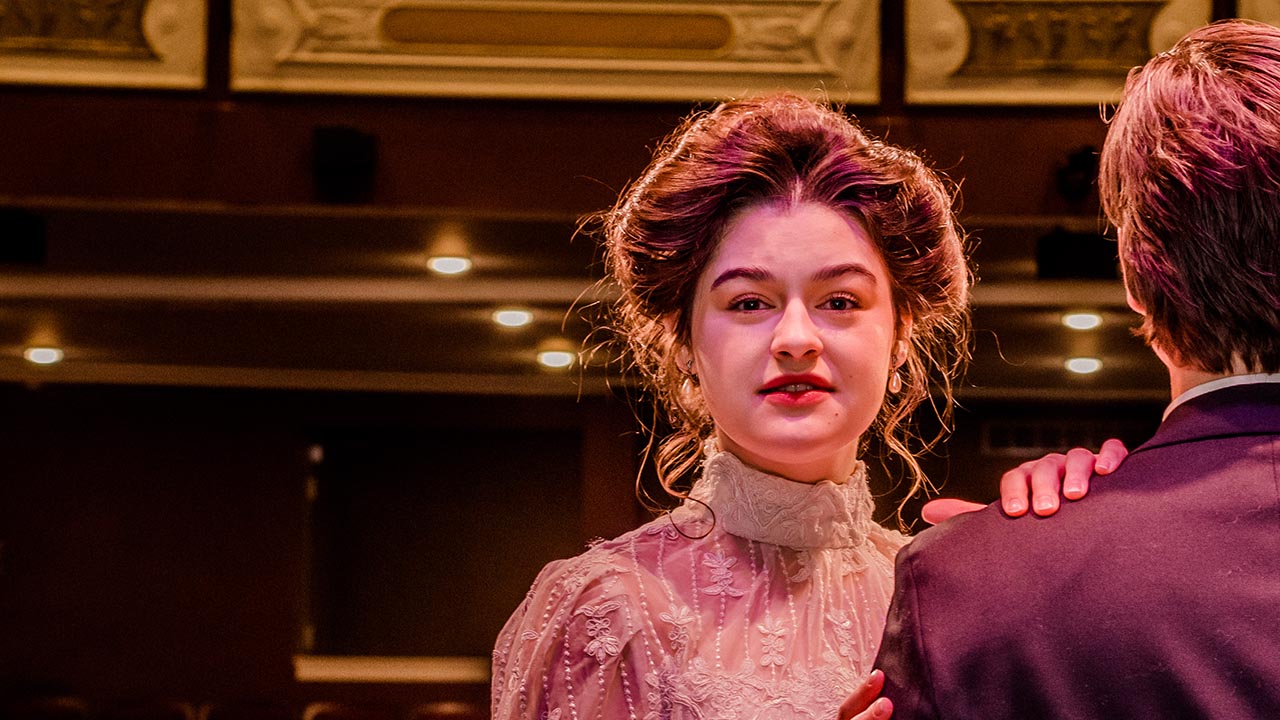 A woman in period costume on a stage.