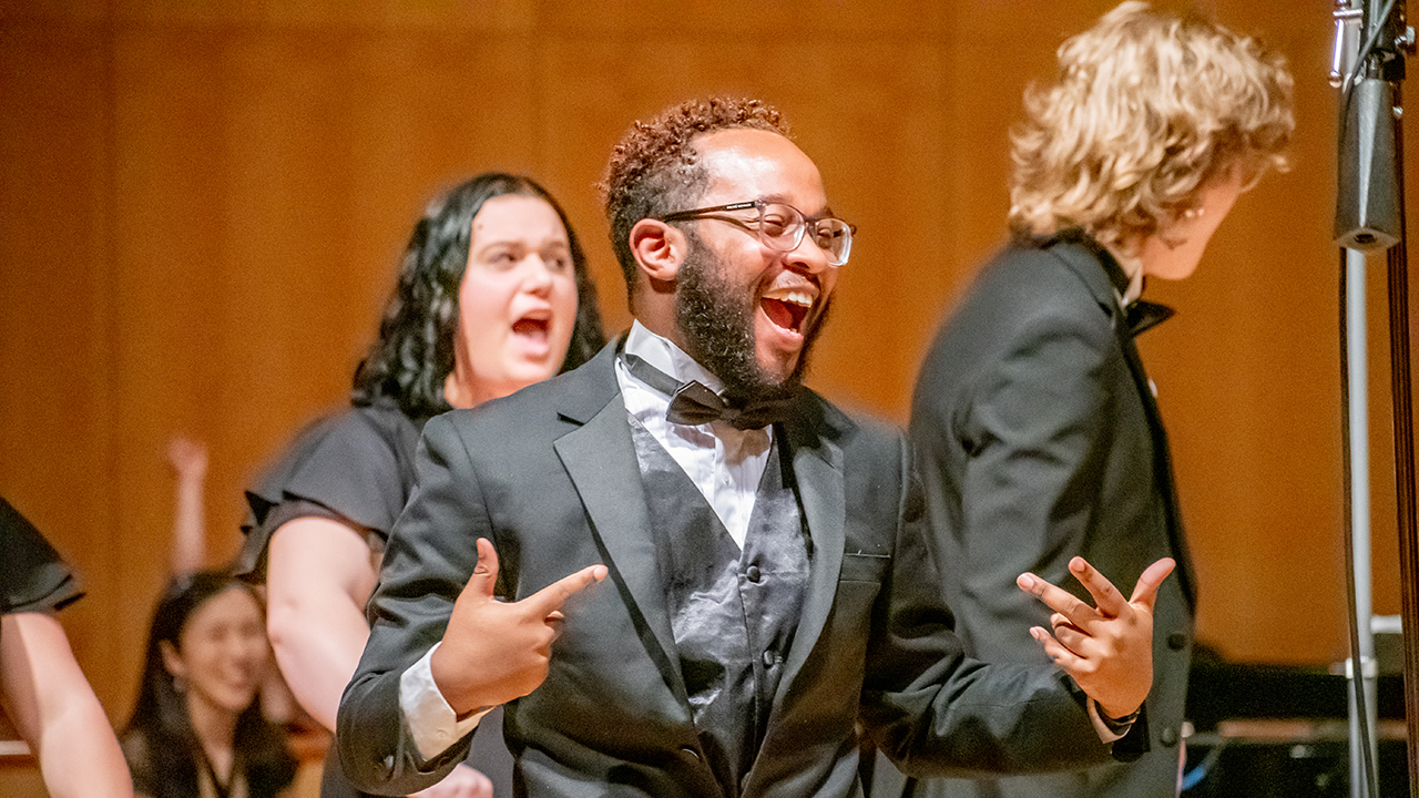 A group of people in matching suits and dresses singing.