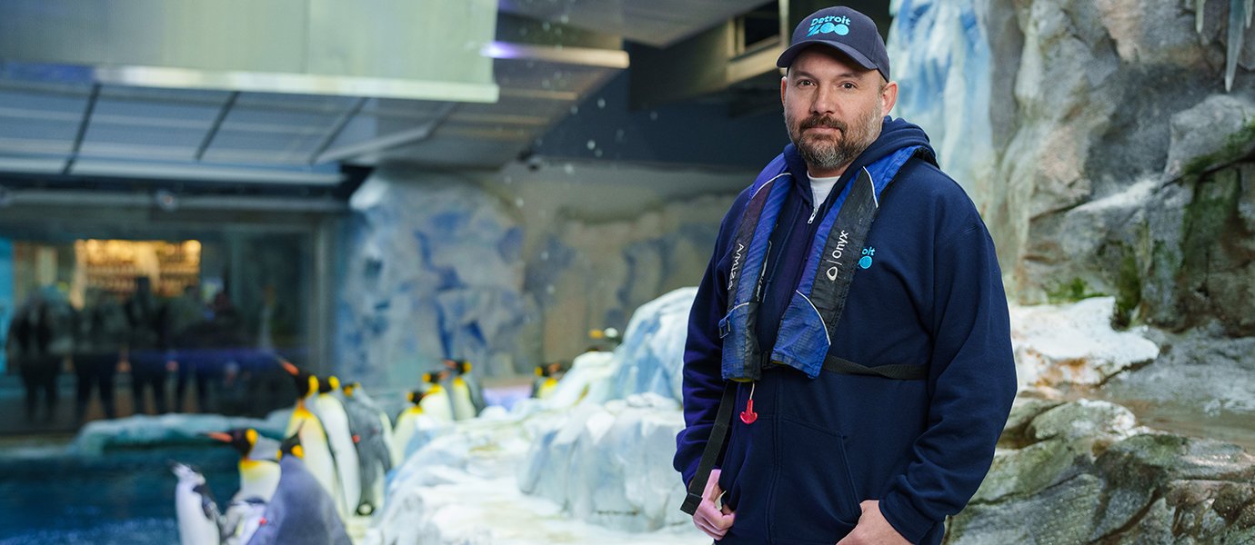 A man in a penguin exhibit
