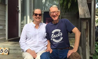 A man and woman sitting on the steps of a front porch