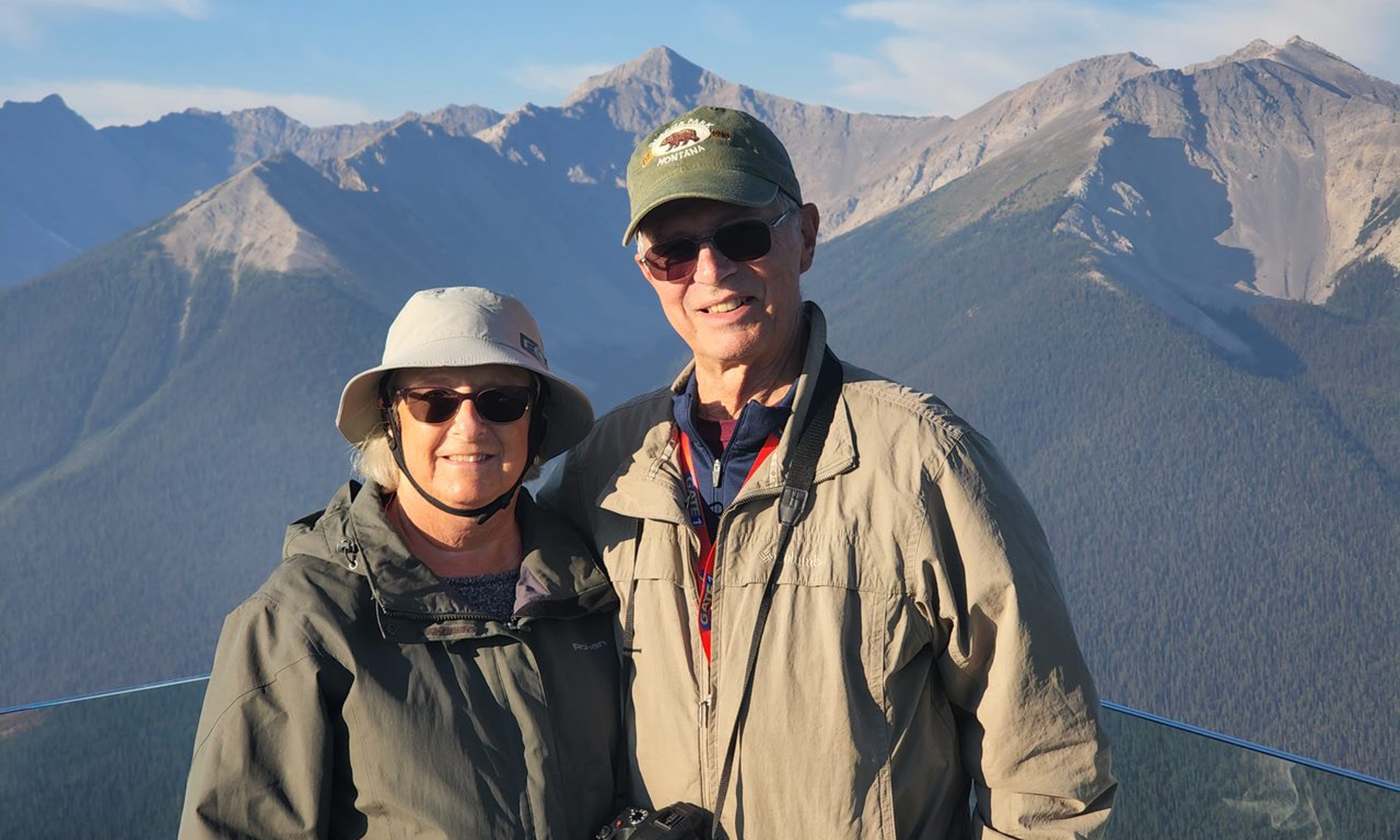 Two people smiling with mountains in the background