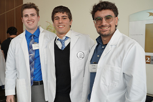 A trio of admitted students trying on white coats