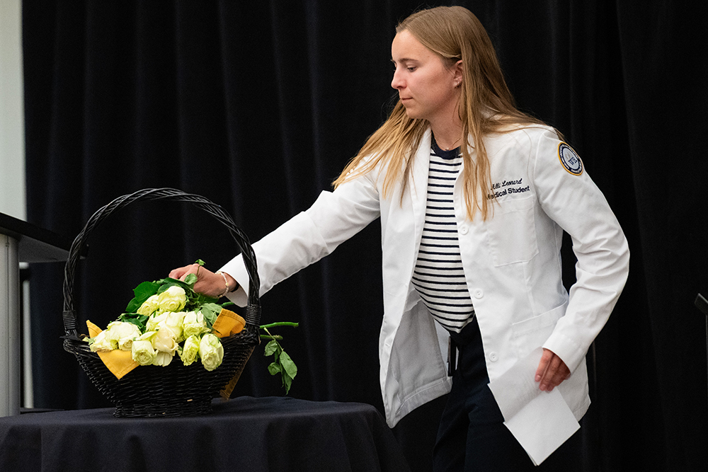 A student setting a flower on a table with other flowers