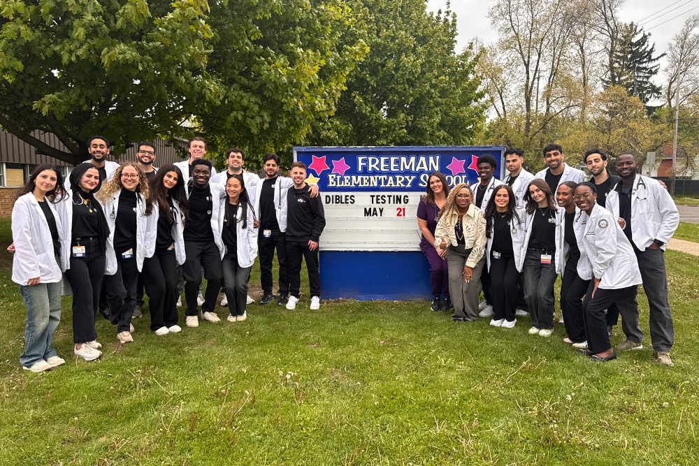 The OUWB cohort near the school sign