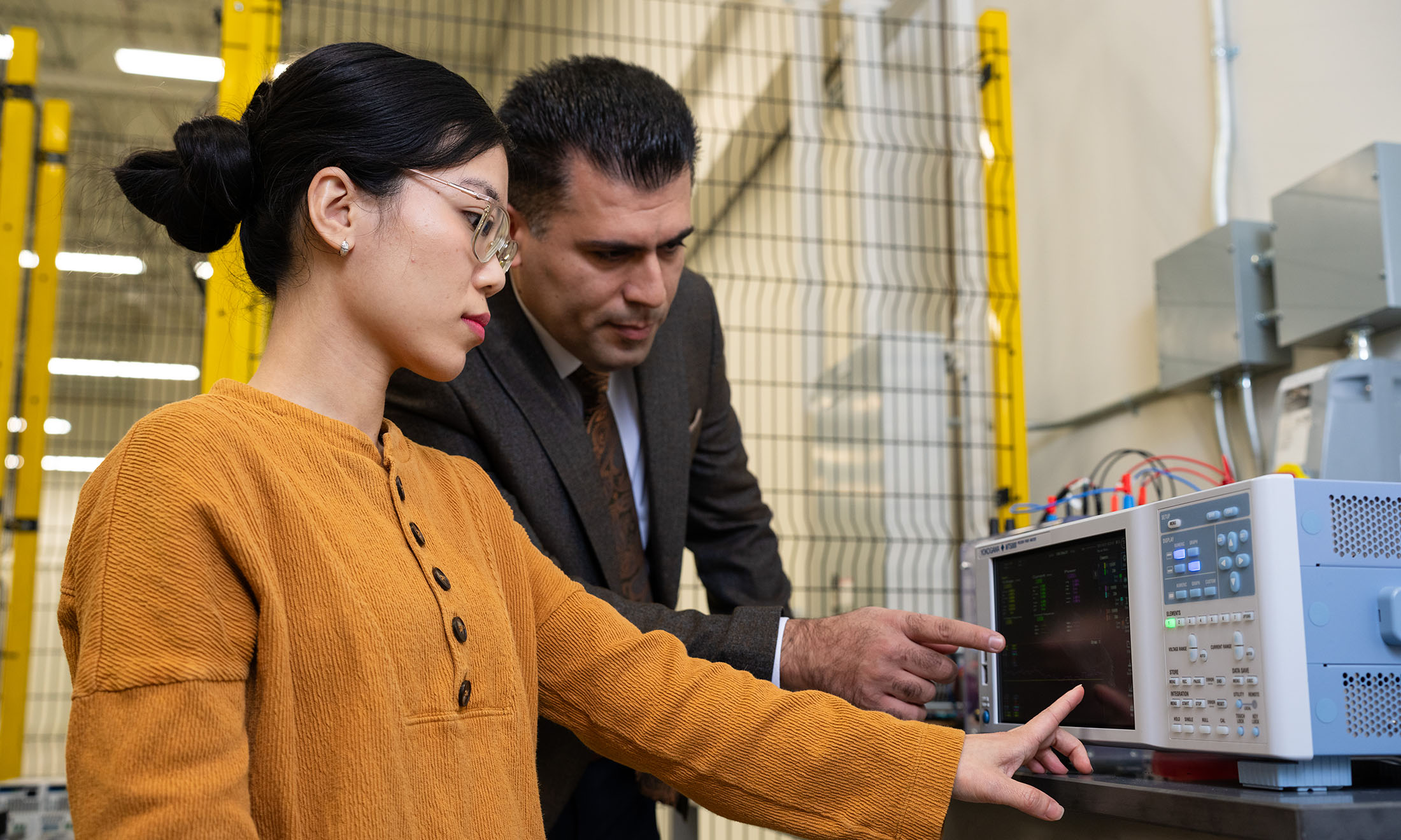 a student and a professor working with equipment at the lab