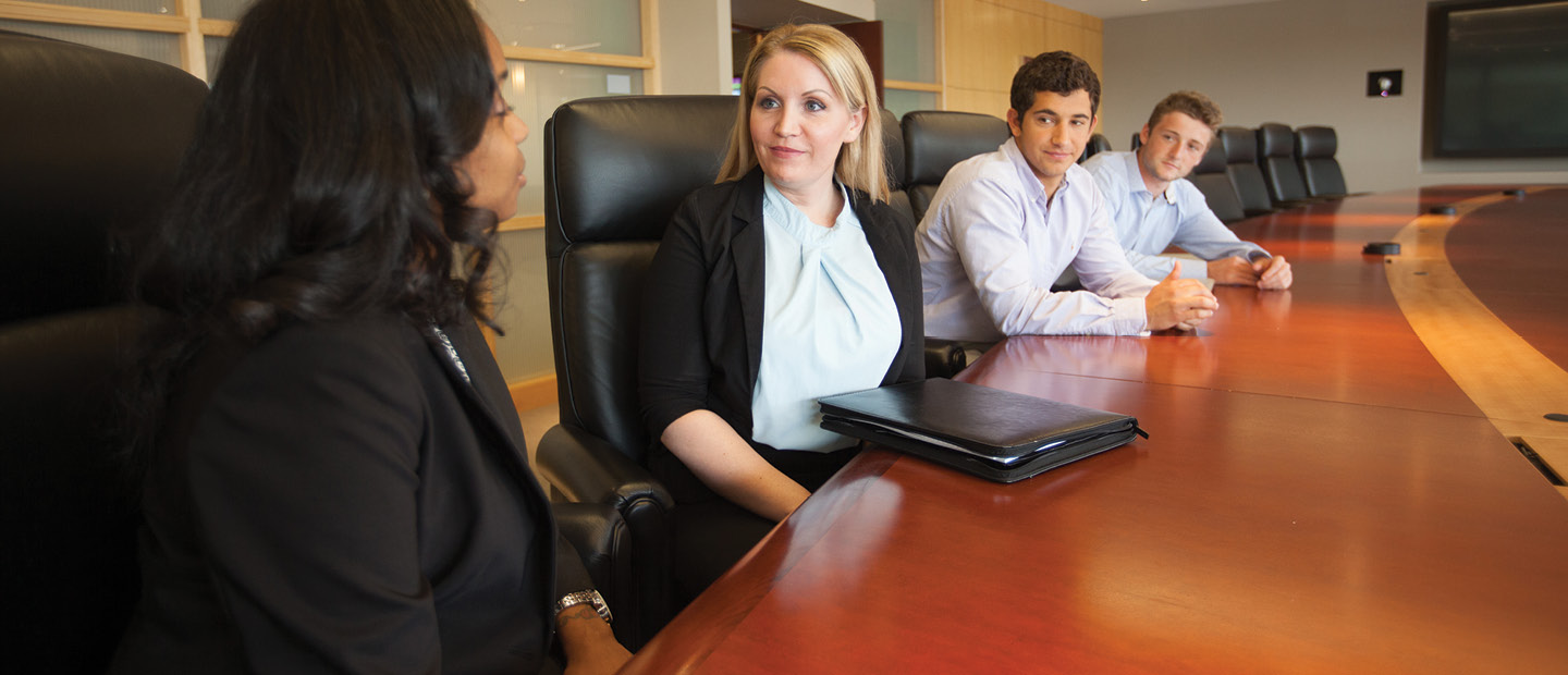 four adults seated in black chairs in a row