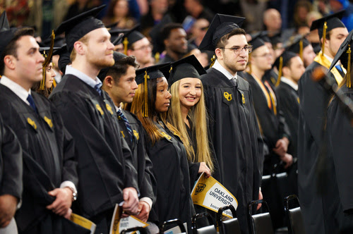 Students in caps and gowns at commencement looking right