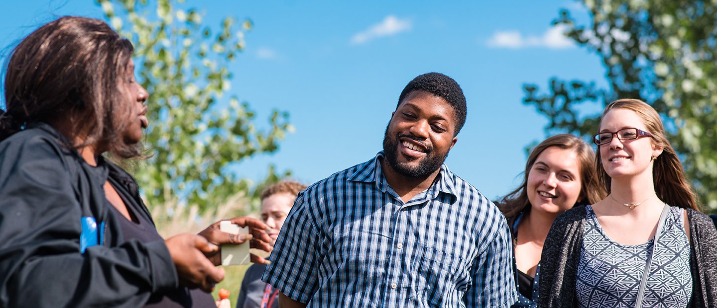 Woman talking to a group of students outdoors