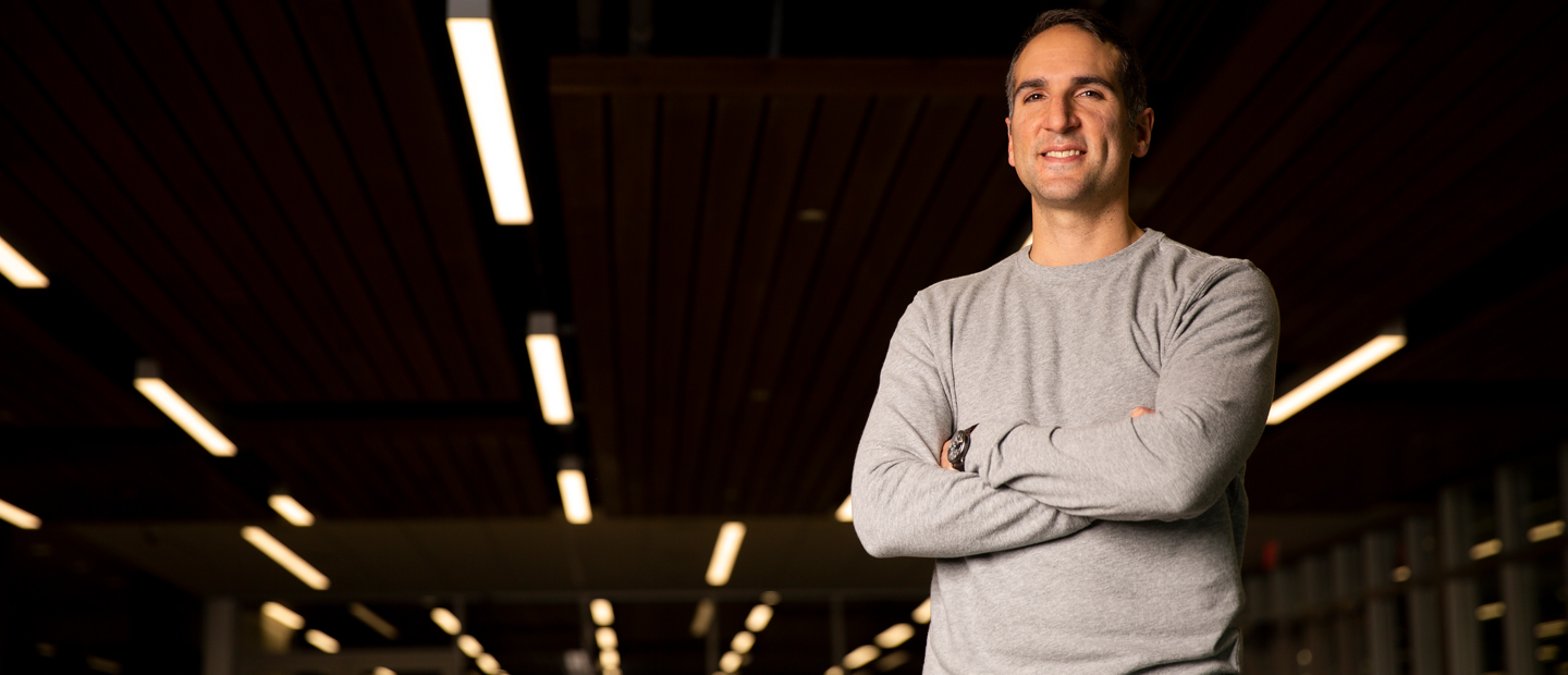 Image of a smiling man standing with his arms crossed