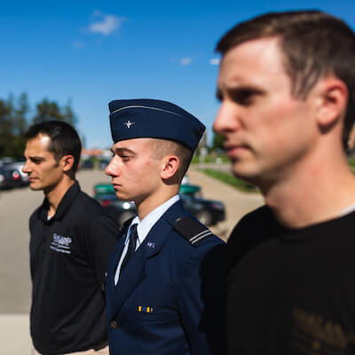 Thee men standing together, one is wearing a military uniform