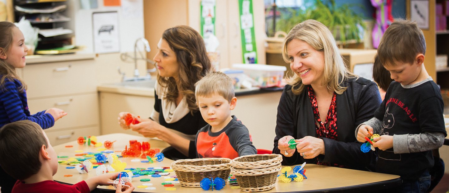 two women sitting at a table with a few children