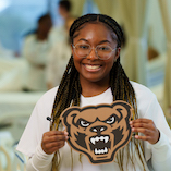 Woman holding a Grizzly mascot sign